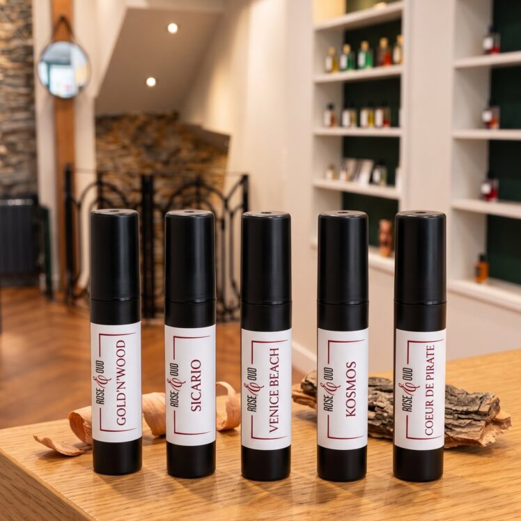 Cinq échantillons 2 ml Rose&Oud boisés posés sur le comptoir de la boutique : Gold’N’Wood, Sicario, Venice Beach, Kosmos, Cœur de Pirate